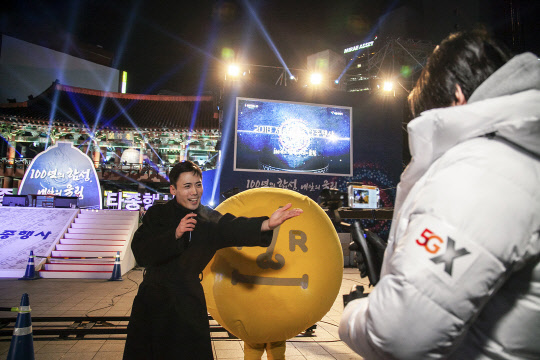 SK텔레콤은 서울 종로 보신각에서 5G 상용망과 생중계 솔루션을 활용한 TV 생방송을 세계 최초로 성공했다고 1일 밝혔다. 'XtvN' 개그맨 조영빈 씨(가운데 검은 코트)가 'T라이브캐스터'를 활용해 생중계하는 모습.  SK텔레콤 제공